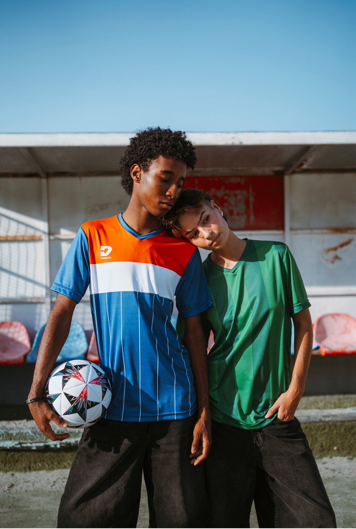 Due ragazzi indossano maglie da calcio Dinicri a bordo campo